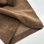 Close-up of brown corduroy fabric showing textured ridges and soft material, ideal for fashion and upholstery applications.
