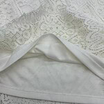Close-up of white lace fabric with intricate floral patterns, perfect for fashion and wedding dress designs.