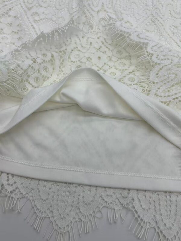 Close-up of white lace fabric with intricate floral patterns, perfect for fashion and wedding dress designs.