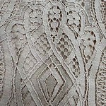 Close-up of detailed lace fabric with geometric and floral patterns, showcasing craftsmanship and delicate texture.