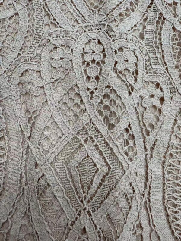 Close-up of detailed lace fabric with geometric and floral patterns, showcasing craftsmanship and delicate texture.