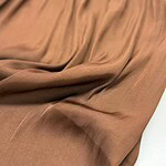 Close-up of soft, flowing brown fabric suitable for fashion and clothing design, showcasing smooth texture and gentle drapes.