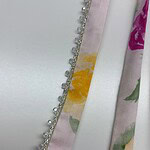 Close-up of a satin ribbon with floral print and decorative pearls, ideal for fashion accessories and garment embellishments.