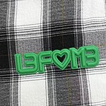 Bright green neon sign spelling 'LAFOME' with a heart symbol in the middle, placed on a black and white checkered fabric background.