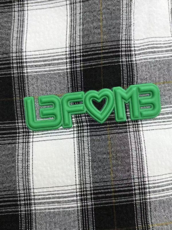 Bright green neon sign spelling 'LAFOME' with a heart symbol in the middle, placed on a black and white checkered fabric background.