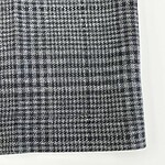 Close-up of a women's skirt with a classic black and white houndstooth pattern, showcasing detailed fabric texture and tailored design.