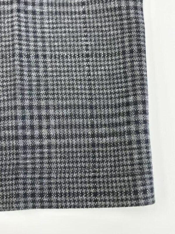Close-up of a women's skirt with a classic black and white houndstooth pattern, showcasing detailed fabric texture and tailored design.