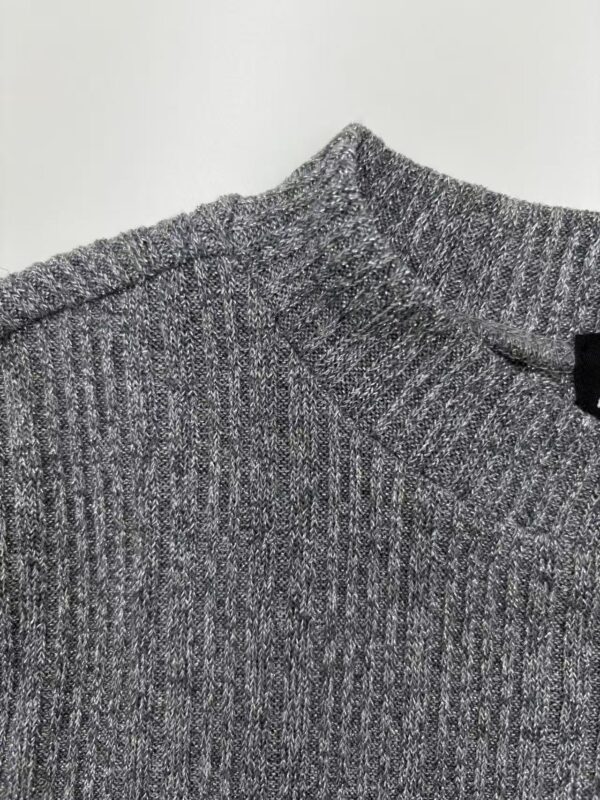 Close-up of a grey knitted sweater with a V-neck, showcasing textured fabric and fine detailing, perfect for casual or office wear.