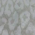 Close-up of a light-colored ikat fabric with intricate, abstract geometric design in soft neutral tones, ideal for stylish clothing and home decor.