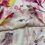 Close-up of floral fabric featuring pink, yellow, and purple flowers on a light background, showcasing delicate watercolor-style design and soft texture.