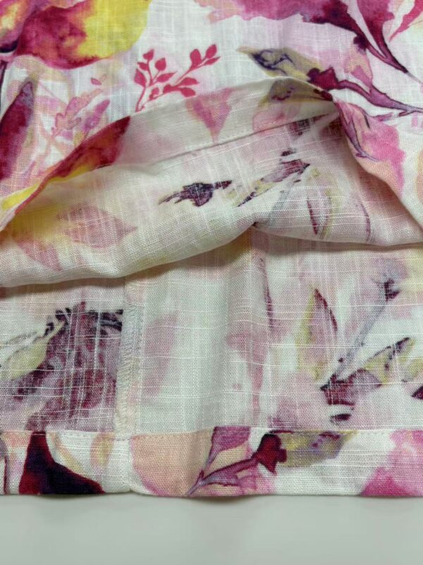 Close-up of floral fabric featuring pink, yellow, and purple flowers on a light background, showcasing delicate watercolor-style design and soft texture.