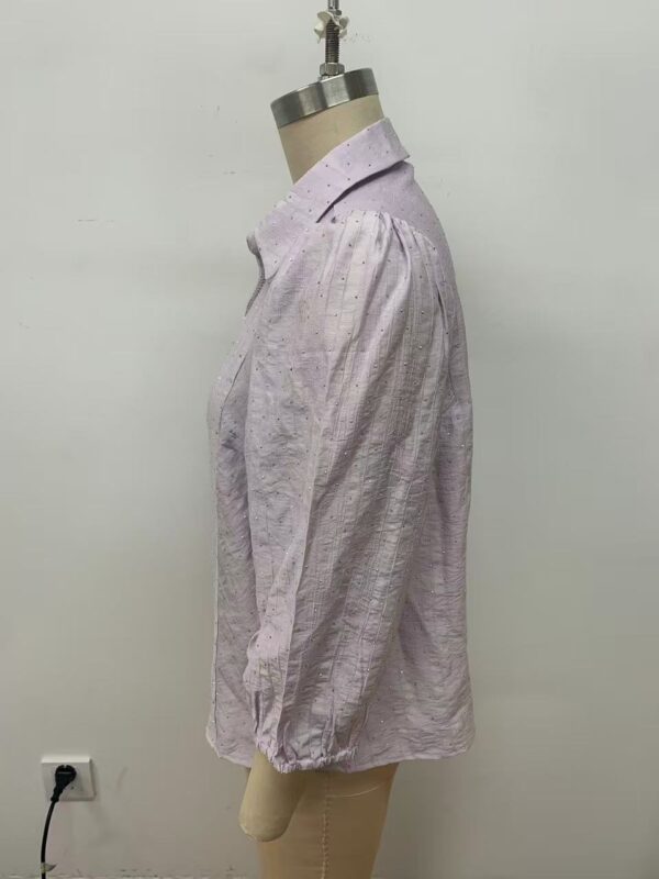 Side view of a light pink linen blouse with long sleeves and a classic collar, displayed on a mannequin against a plain white background.