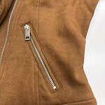 Close-up of a brown leather jacket with a silver zipper pocket, showcasing high-quality craftsmanship and trendy fashion style.