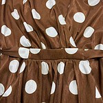 Close-up of a brown dress with white polka dots, featuring a gathered waist and fabric belt, perfect for casual or semi-formal occasions.