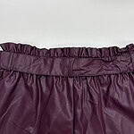 Close-up of a high-quality burgundy leather skirt with a ruffled elastic waistband, perfect for fashionable women's wardrobe.