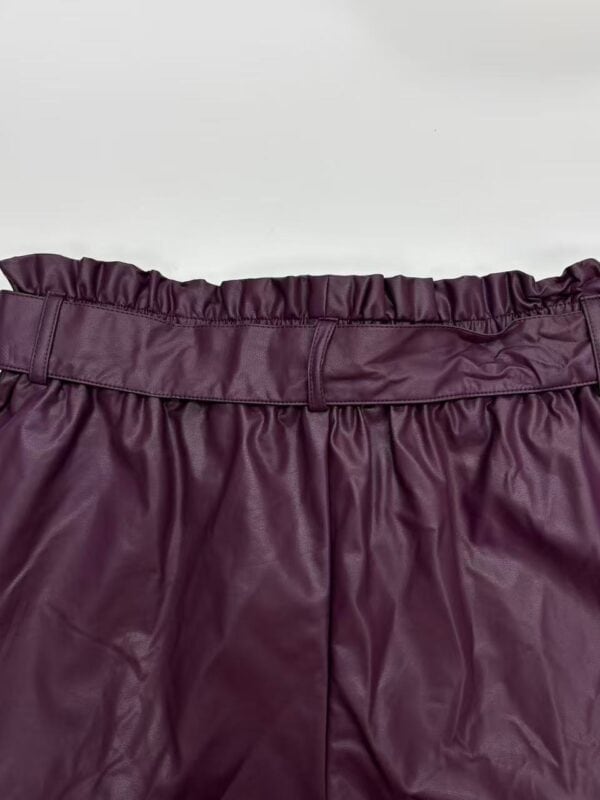Close-up of a high-quality burgundy leather skirt with a ruffled elastic waistband, perfect for fashionable women's wardrobe.