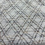 Close-up of a textured rug with a geometric diamond pattern in neutral tones, ideal for modern home decor.