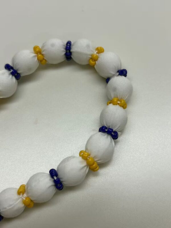 Colorful handmade beaded necklace featuring white fabric beads with blue and yellow accents, perfect for stylish accessories.