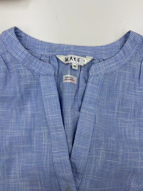 Close-up of a blue checkered women's shirt with a round neckline and button closure, suitable for casual or office wear.