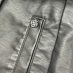 Detailed view of a black leather jacket with a silver zipper pull featuring a logo, showcasing the texture and craftsmanship of the material.