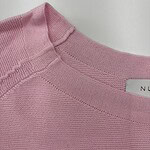 Close-up of a pink knitted sweater showing the neckline and fabric texture, ideal for women's fashion and casual wear.