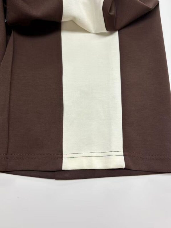 Close-up of a stylish brown dress with a contrasting cream panel, showcasing high-quality fabric and craftsmanship for fashion enthusiasts.
