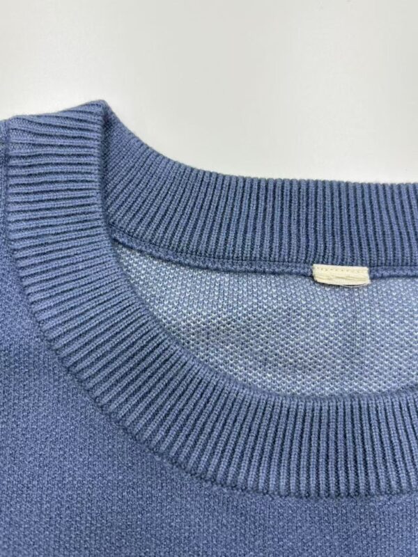 Close-up of a blue knitted sweater showcasing the ribbed neckline and textured fabric, ideal for casual and stylish wear.
