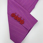 Close-up of a purple suit sleeve with subtle pinstripes and four red buttons, showcasing stylish tailoring and vibrant color for fashion enthusiasts.