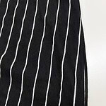 Close-up of black fabric with white vertical pinstripes, showcasing a stylish and classic pattern suitable for fashion apparel.