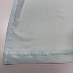 Close-up of light blue fabric with stitched edge, showing fine texture and smooth finish, ideal for fashion or textile product display.