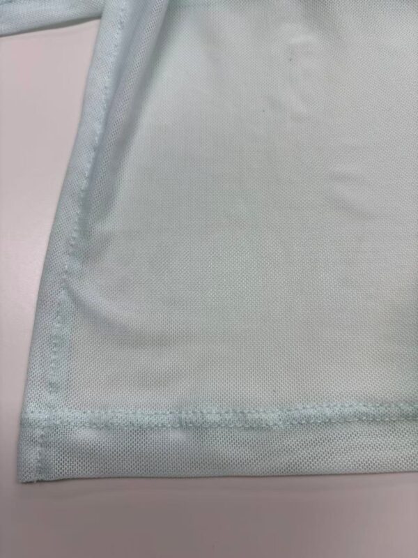 Close-up of light blue fabric with stitched edge, showing fine texture and smooth finish, ideal for fashion or textile product display.