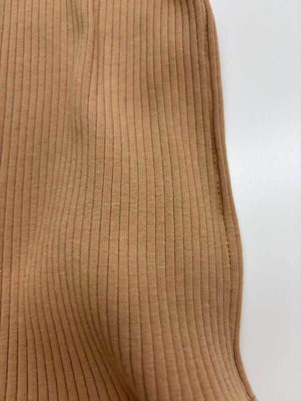 Close-up of a tan ribbed knit dress showing vertical lines and soft texture, perfect for casual or elegant wear.