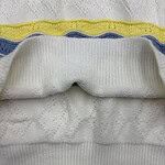 Detailed view of white fabric with colorful yellow and blue stripes, showcasing texture and stitching details.