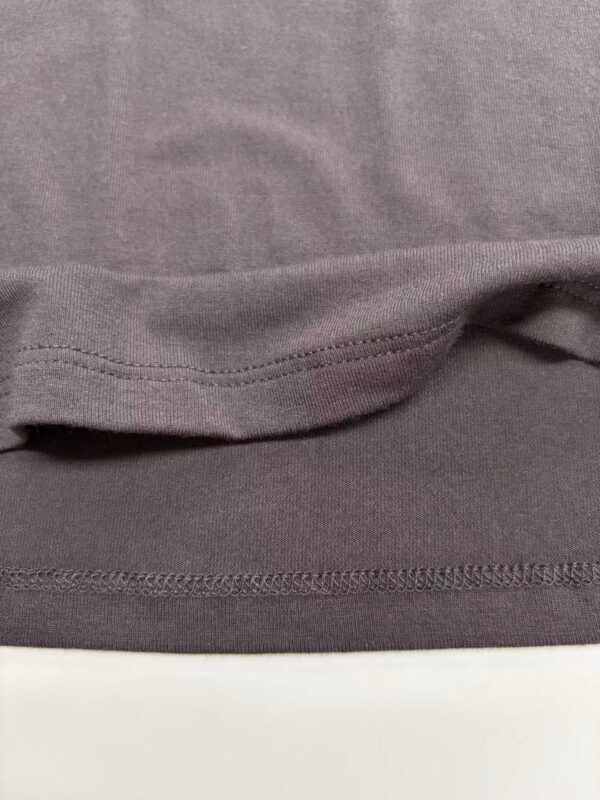 Detailed close-up of fabric hem showing stitching and texture, highlighting quality and craftsmanship of clothing from nbfish-fashion.com.