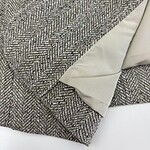 Close-up of a sophisticated tweed fabric with a smooth silk lining, showcasing high-quality craftsmanship and classic style for fashion or interior design.