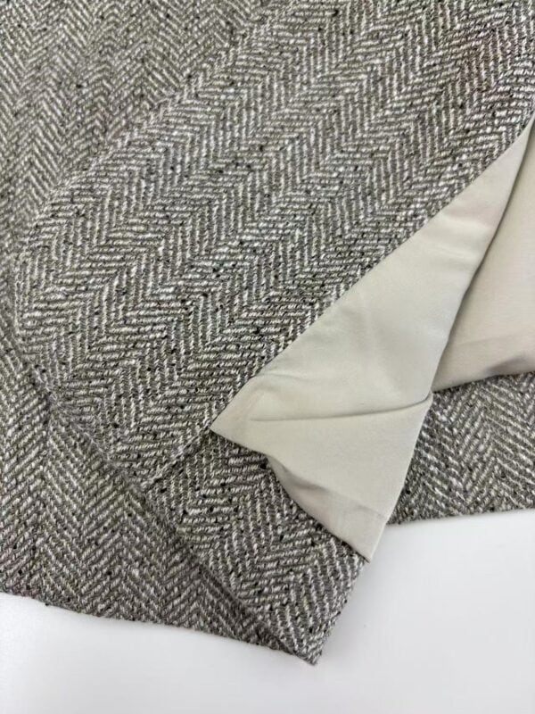 Close-up of a sophisticated tweed fabric with a smooth silk lining, showcasing high-quality craftsmanship and classic style for fashion or interior design.
