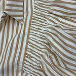 Close-up of a beige and white striped linen dress featuring a smocked waist and a collar, perfect for casual summer wear.