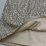 Close-up of a glamorous dress featuring silver sequins and smooth satin lining, perfect for special occasions and evening wear.