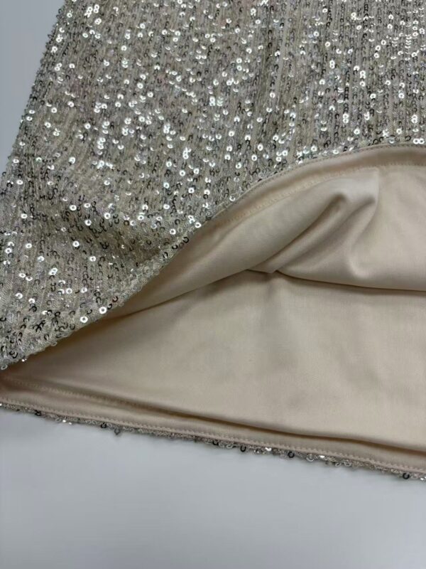 Close-up of a glamorous dress featuring silver sequins and smooth satin lining, perfect for special occasions and evening wear.