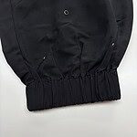 Close-up of black fashion pants featuring metal eyelets and elastic waistband, suitable for stylish casual wear.