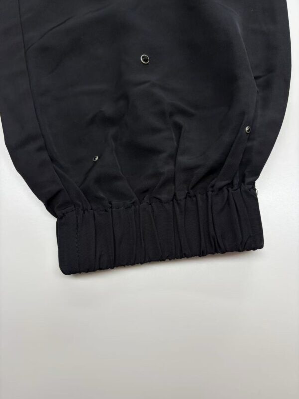 Close-up of black fashion pants featuring metal eyelets and elastic waistband, suitable for stylish casual wear.