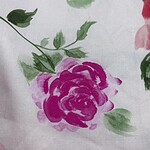 Close-up of a floral fabric with pink and green watercolor-style roses and leaves, ideal for fashion and home decor.