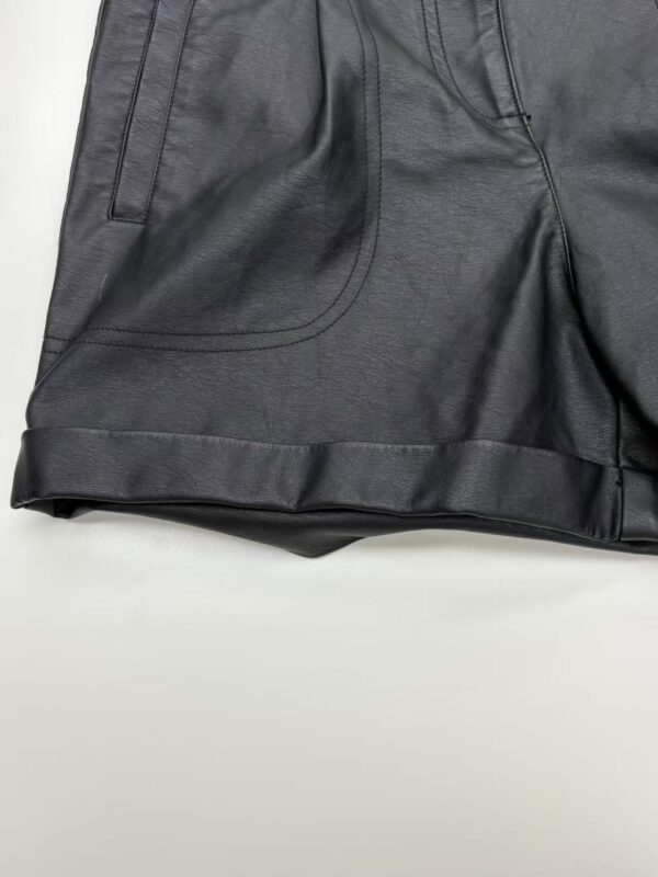 Close-up of stylish black leather shorts with detailed stitching and design, perfect for modern fashion and streetwear looks.