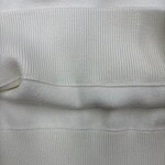 Close-up of white ribbed knit fabric showing detailed texture and fine vertical lines, ideal for fashion and clothing design.