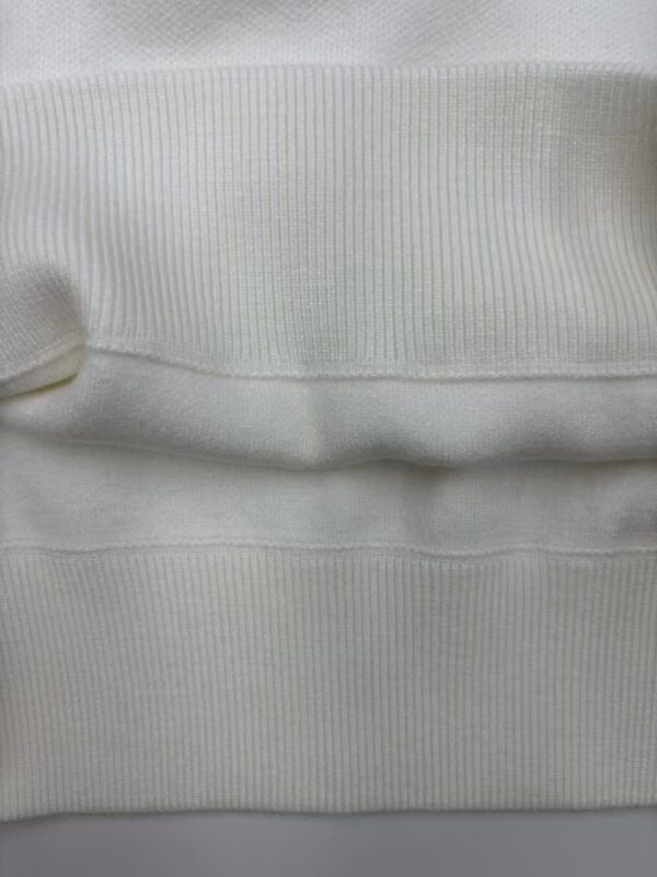 Close-up of white ribbed knit fabric showing detailed texture and fine vertical lines, ideal for fashion and clothing design.