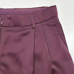 Close-up of stylish burgundy women's trousers with tailored fit and pleats, perfect for professional or casual wear.