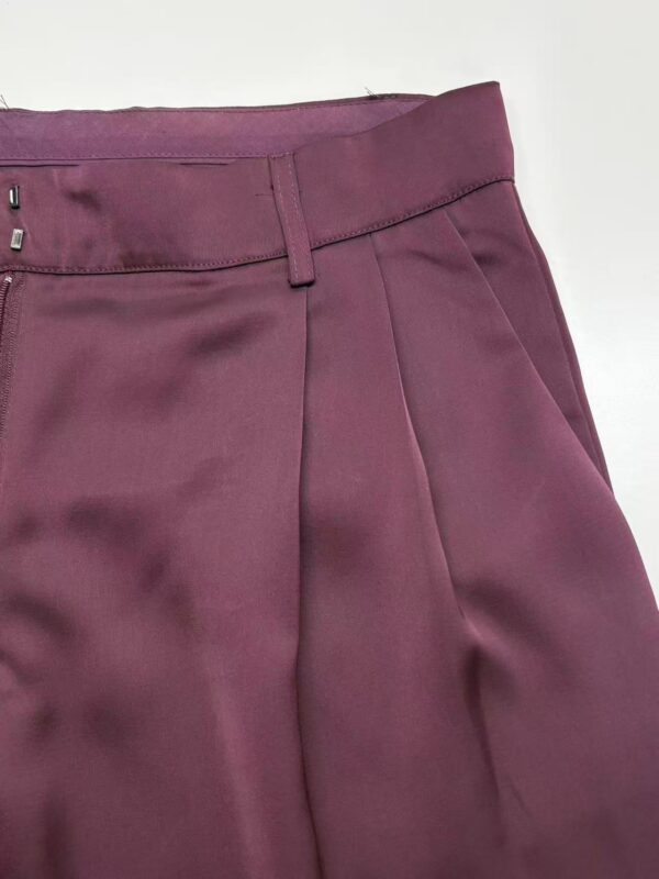 Close-up of stylish burgundy women's trousers with tailored fit and pleats, perfect for professional or casual wear.