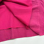 Close-up of vibrant pink linen fabric with detailed texture and stitching, showcasing high-quality material suitable for fashion and home decor.
