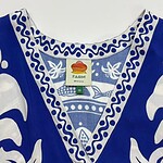 Close-up of a blue and white traditional dress with intricate patterns and embroidery, featuring a farm tag indicating size XS.
