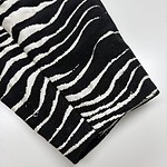 Close-up of black and white zebra print fabric, showcasing bold stripes suitable for stylish clothing and accessories.